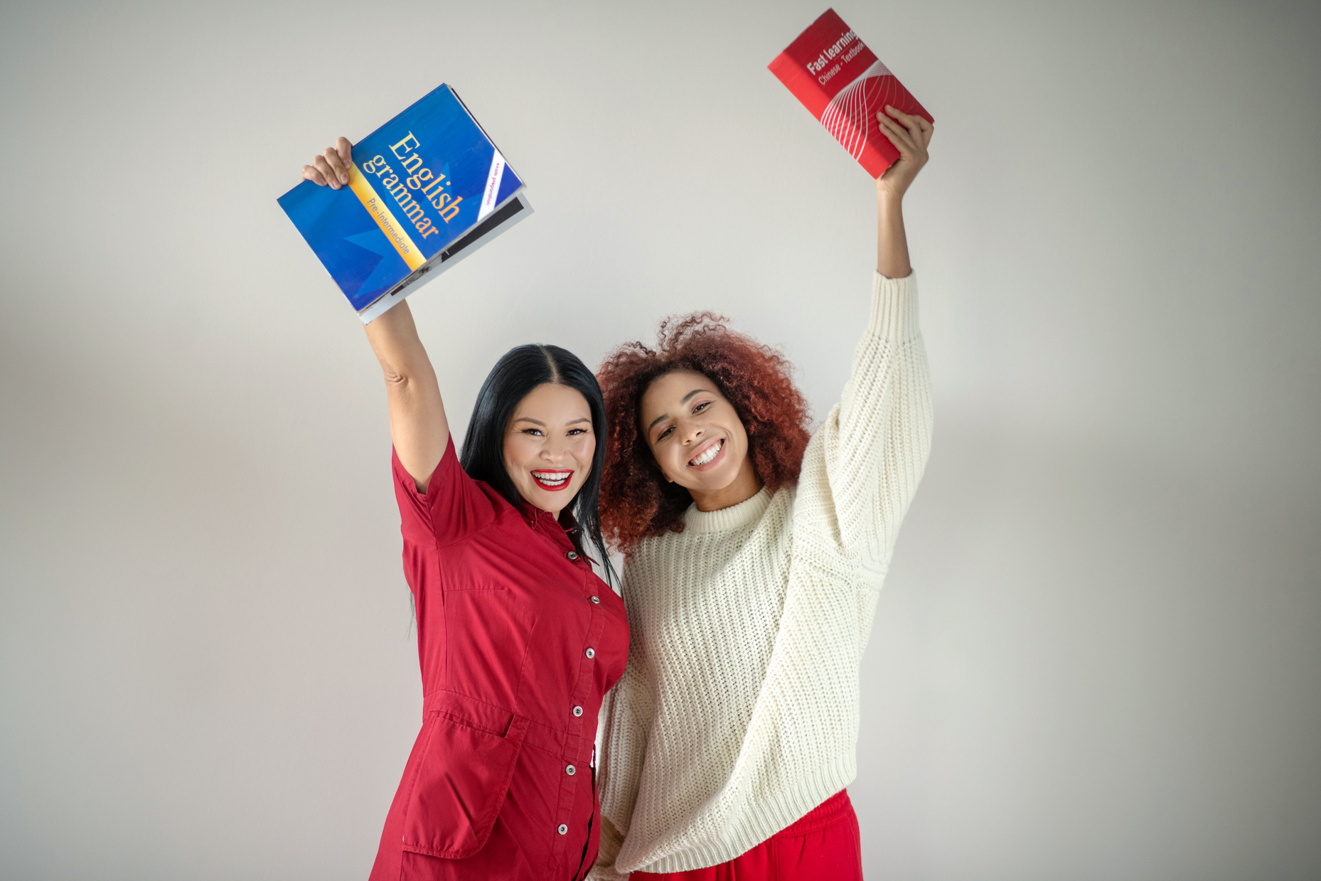 Beaming female friends studying English language together